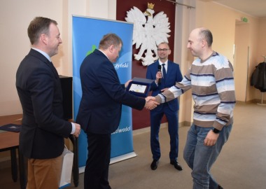 Piotr Dolata odbiera od starosty leszczyńskiego Jarosława Wawrzyniaka i wicestarosty Macieja Wiśniewskiego gratulacje z okazji zdobycia tytułu Geodety 2022 roku w powiecie leszczyńskim