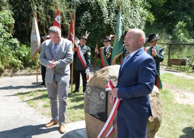 Starosta leszczyński Jarosław Wawrzyniak i burmistrz Rydzyny Kornel Malcherek przed obeliskiem  z płytą upamiętniającą założycieli Kurkowego Bractwa Strzeleckiego w Rydzynie